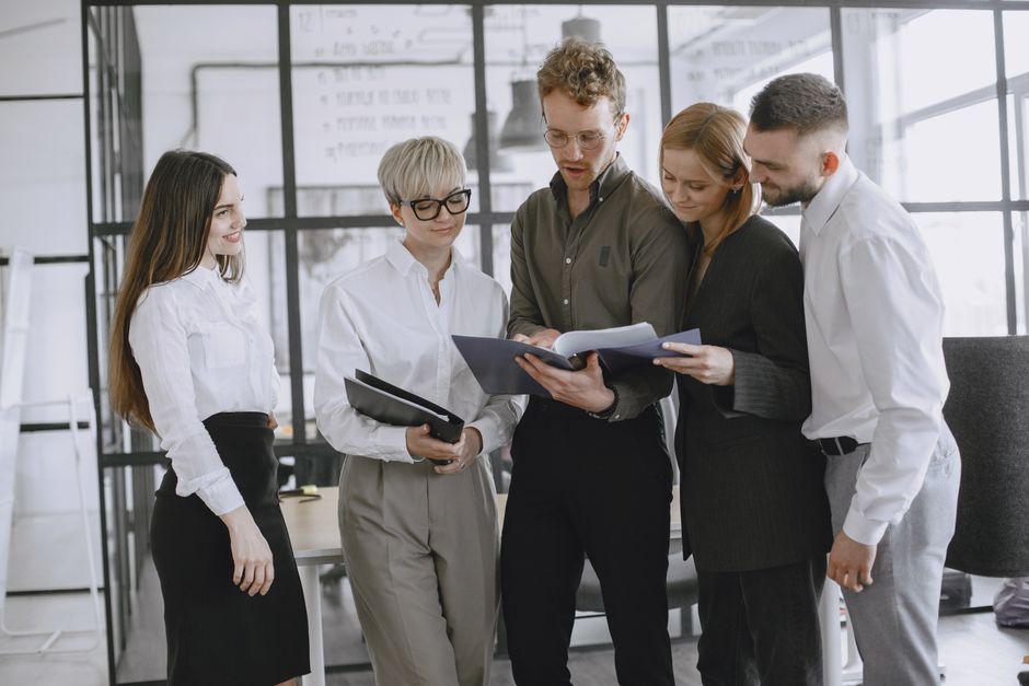 A diverse group of professionals collaborating and discussing documents in a modern office space.