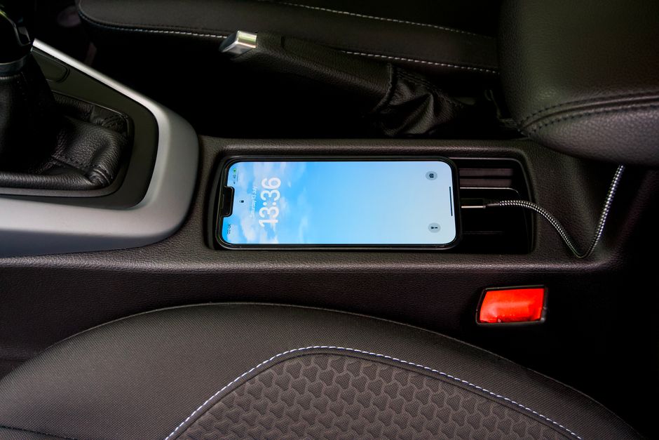 A smartphone charging in a car's central console, showcasing modern automotive technology.
